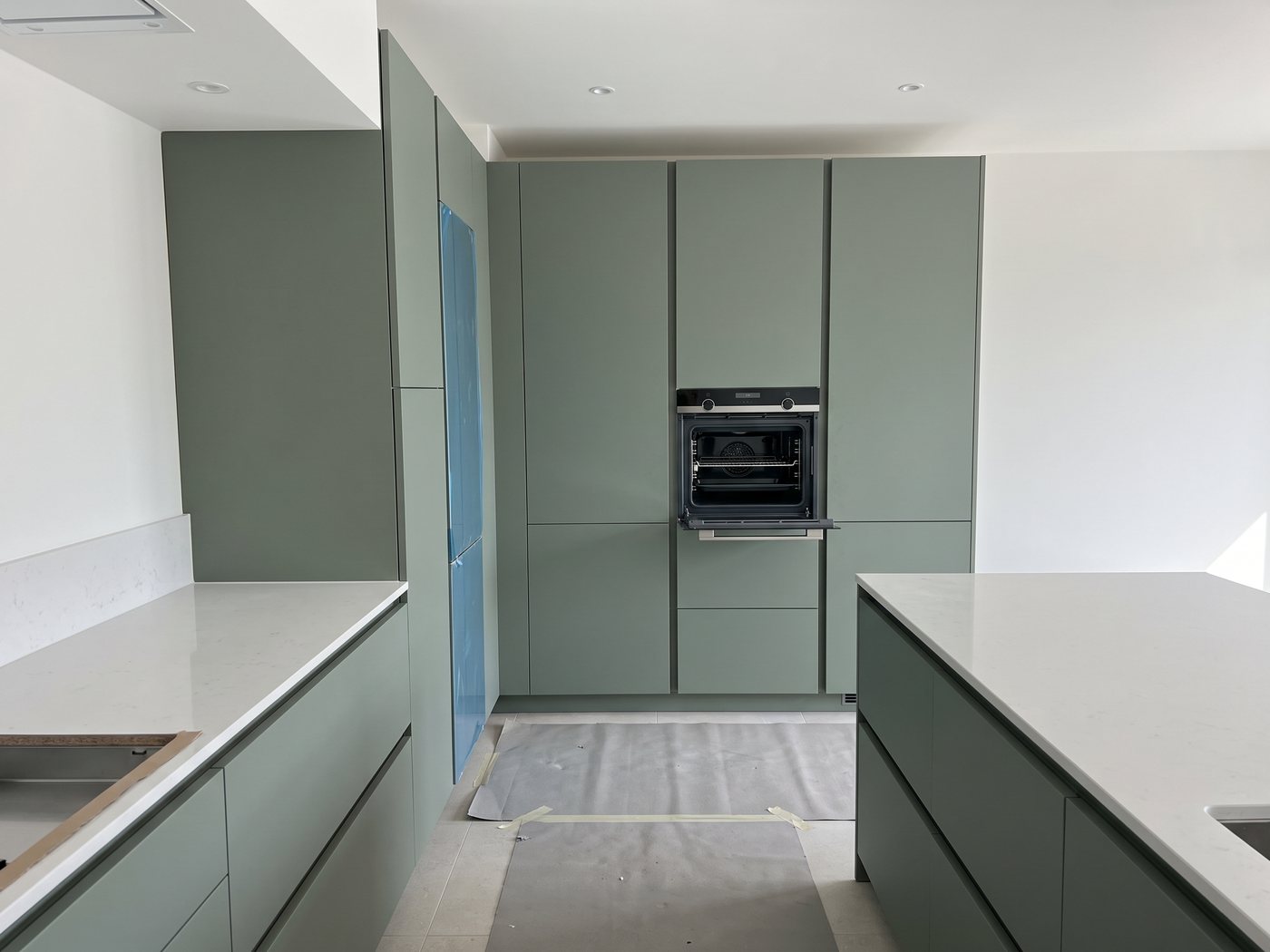 Saliegroene keuken op de dag van de plaatsing, met beschermkarton nog op de vloer